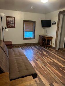 Interior of a comfortable motel room with a sofa, TV, and wooden accents in Meeteetse, Wyoming.